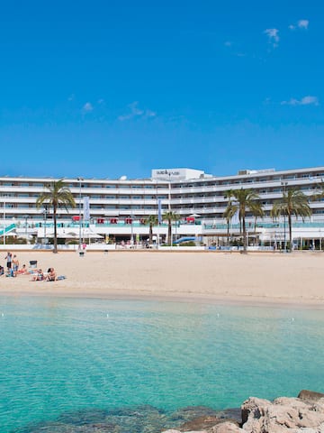 a beach with a large building and palm trees