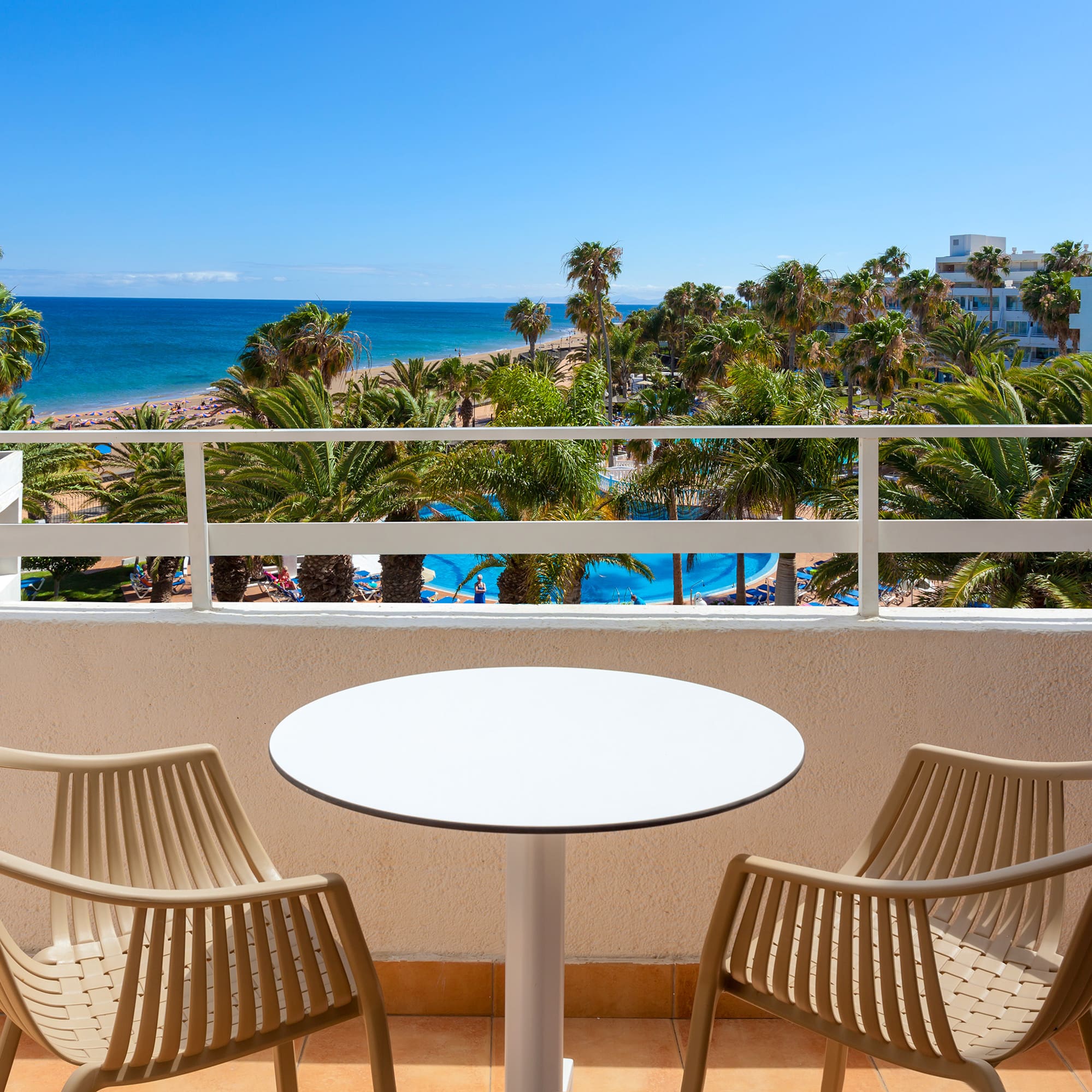 a table and chairs on a balcony overlooking a beach