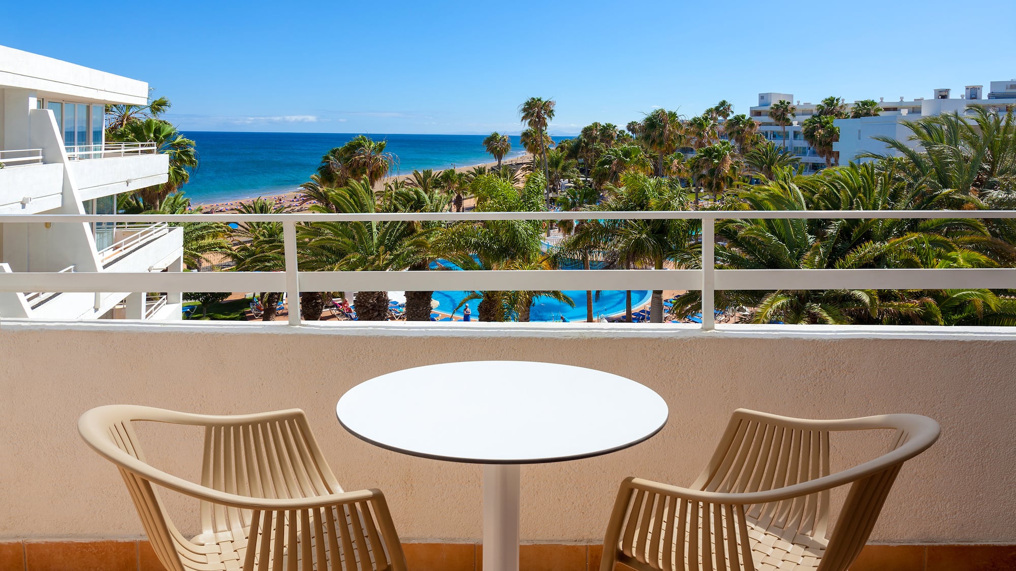 a table and chairs on a balcony overlooking a beach