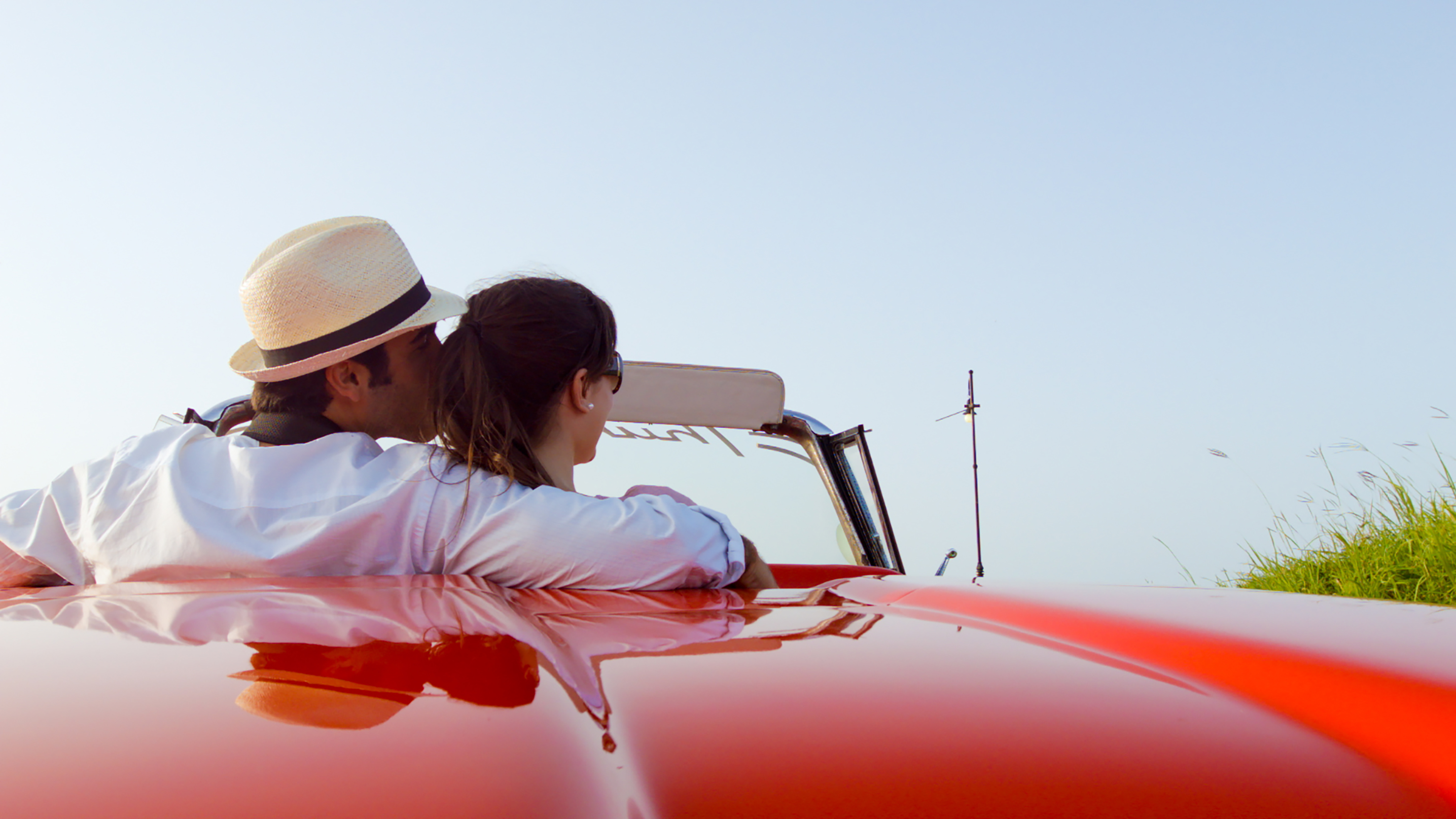 a man and woman sitting on a red car
