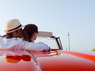 a man and woman sitting on a red car