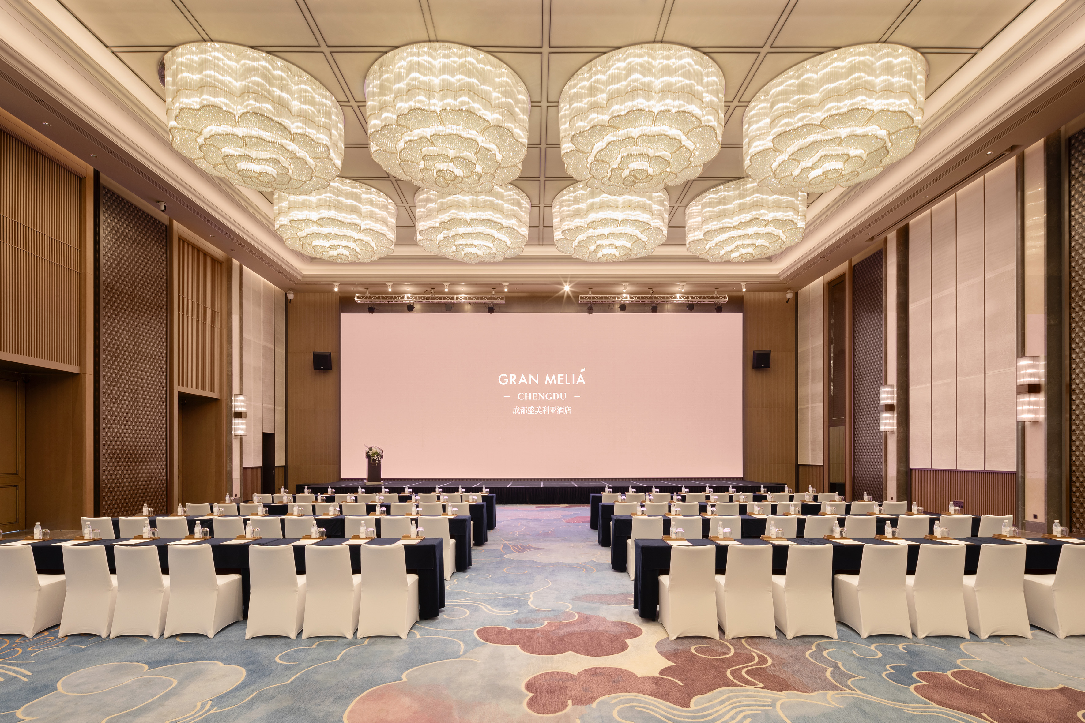 Gran Meliá Chengdu conference room with elegant chandeliers and large screen.