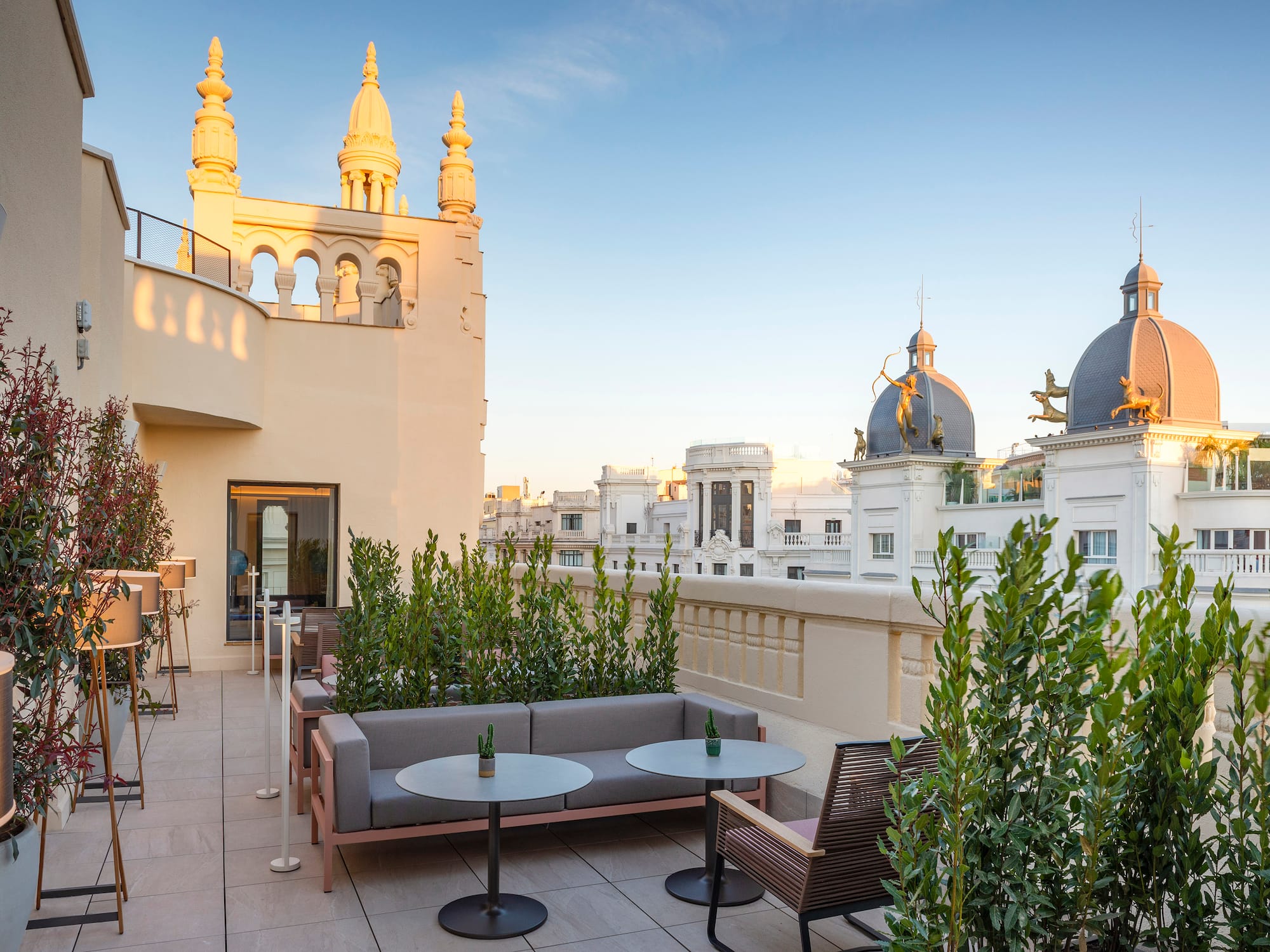 a rooftop patio featuring a table, chairs, and plants