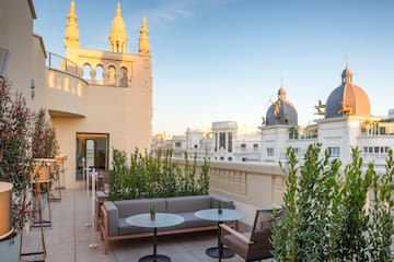 a patio with a table and chairs and plants on a rooftop
