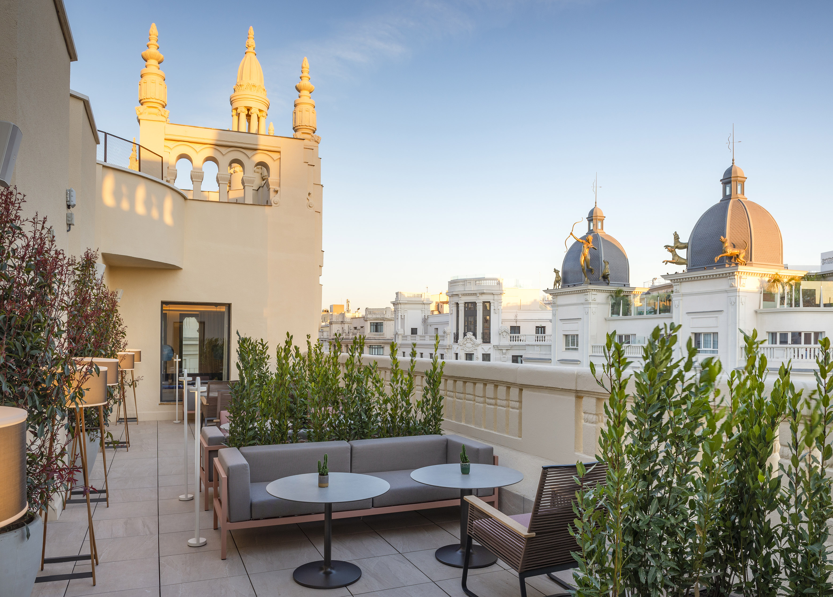 a rooftop patio featuring a table, chairs, and plants