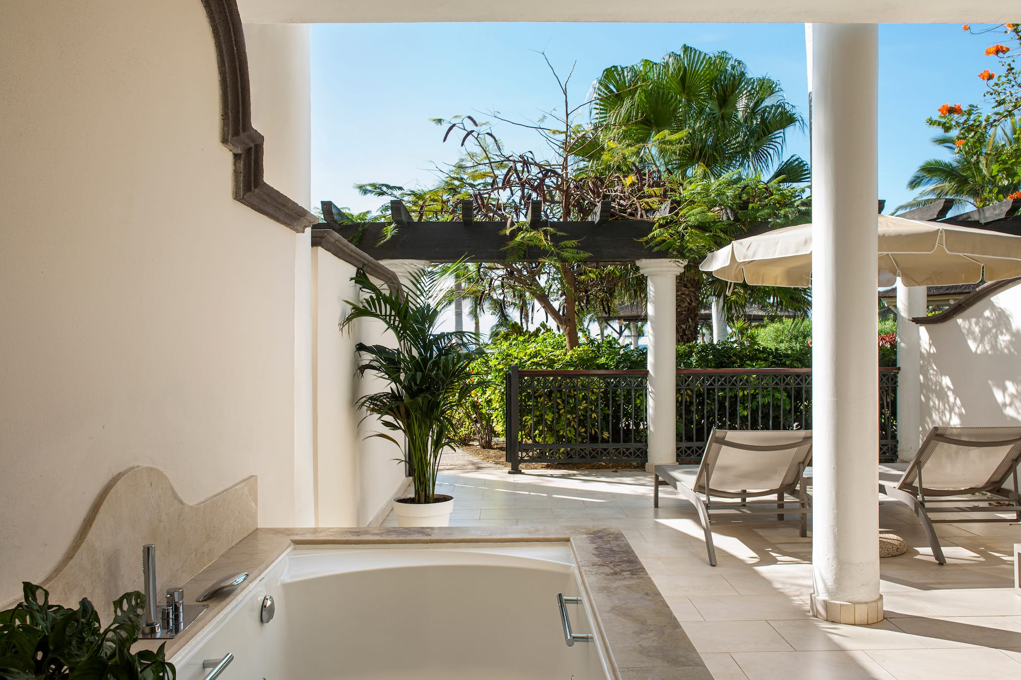 a white patio with a hot tub and chairs