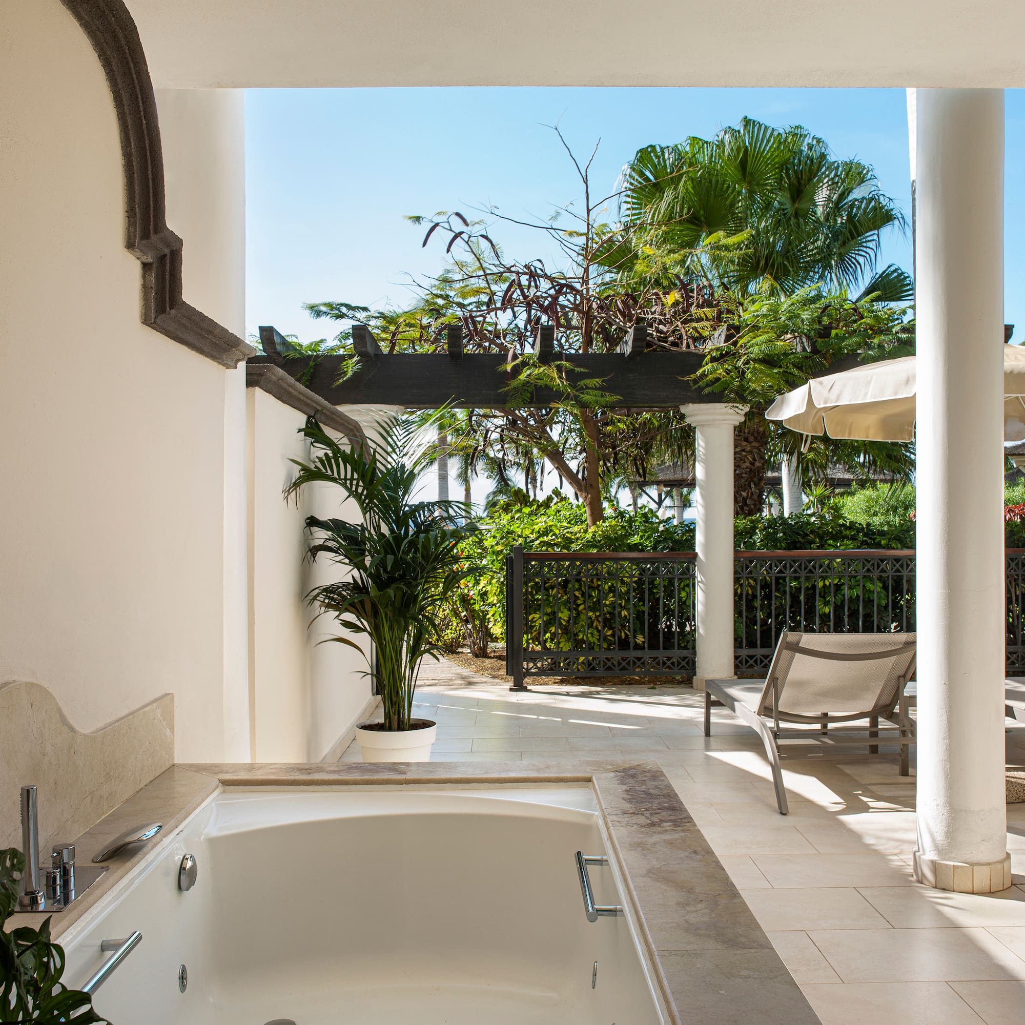 a white patio with a hot tub and chairs