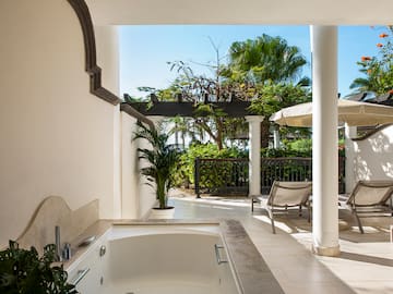 a white patio with a hot tub and chairs