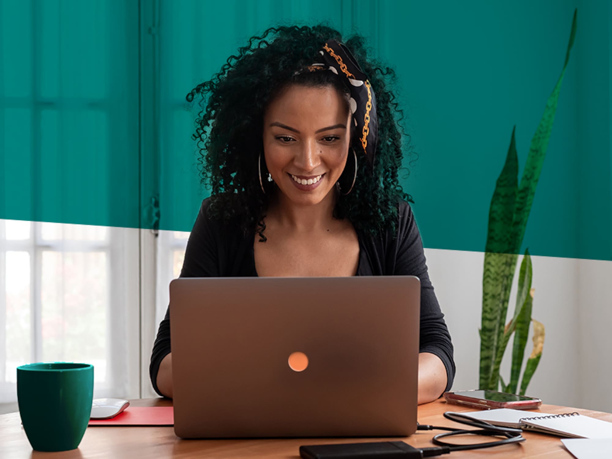 A woman sits at a desk, focused on her laptop.