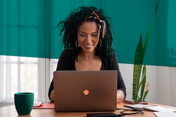 A woman sits at a desk, focused on her laptop.