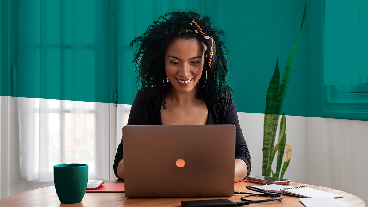 A woman sits at a desk, focused on her laptop.