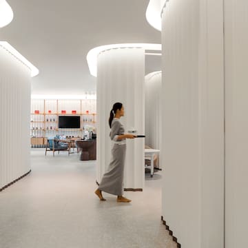 a woman walking in a room with columns