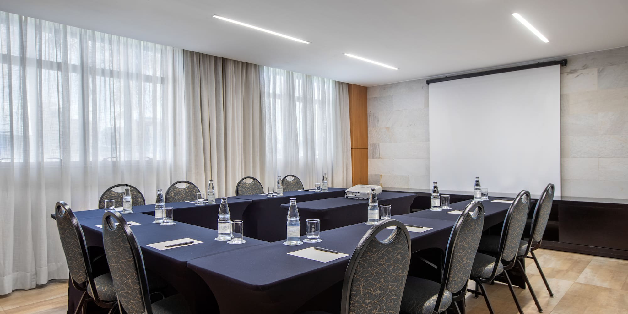a room with a projection screen and tables and chairs