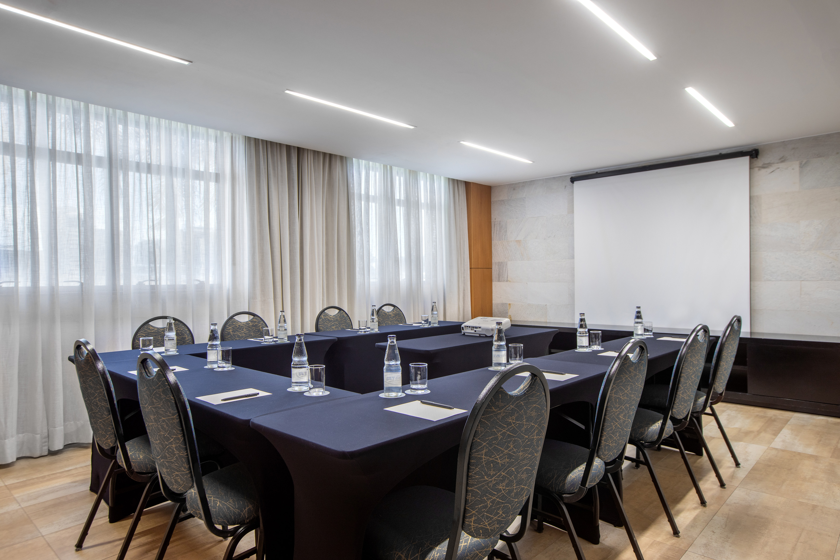 a room with a projection screen and tables and chairs