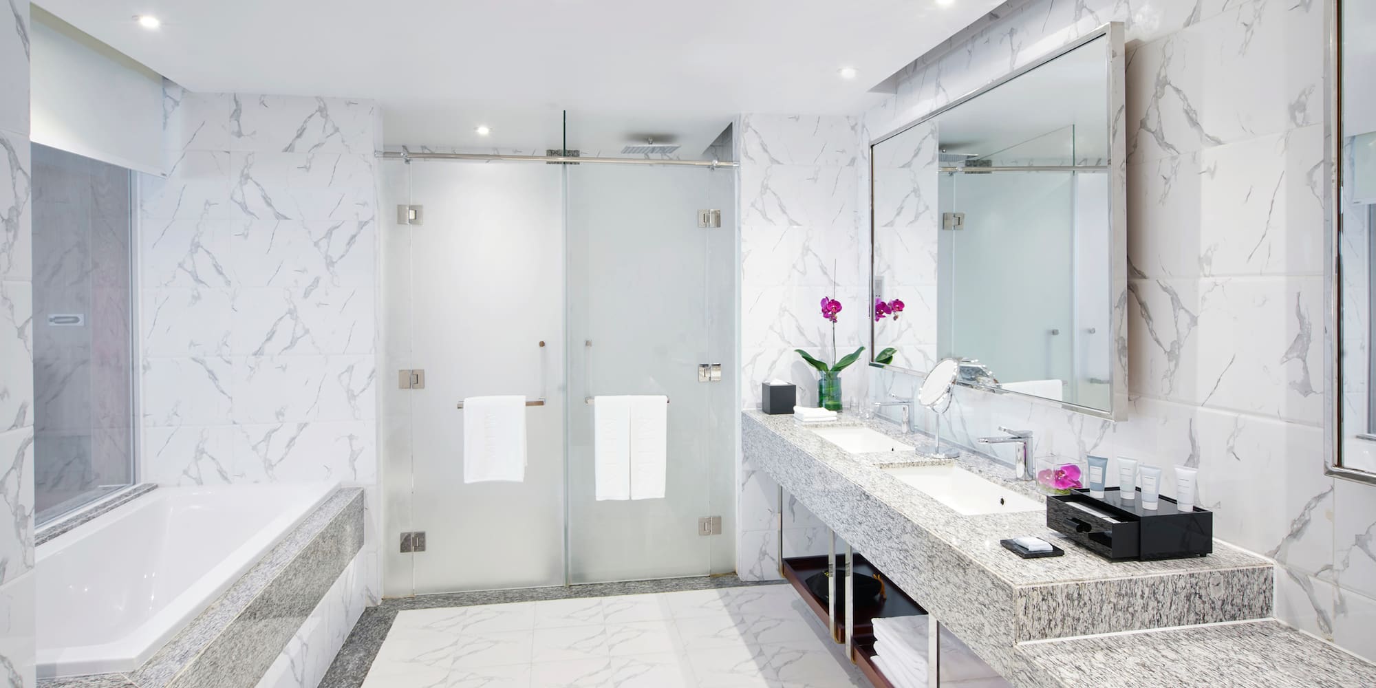 a bathroom with marble countertop sinks and a shower