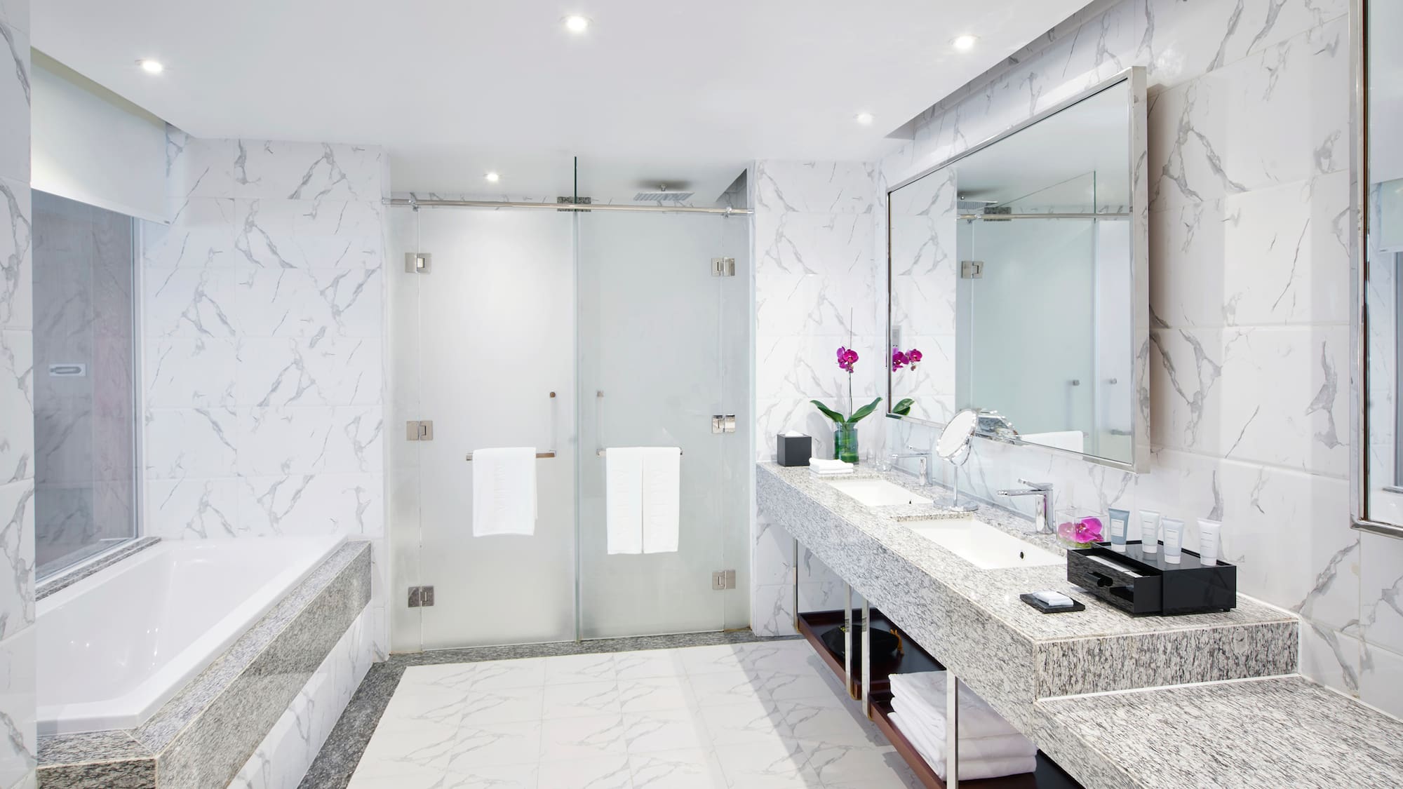 a bathroom with marble countertop sinks and a shower