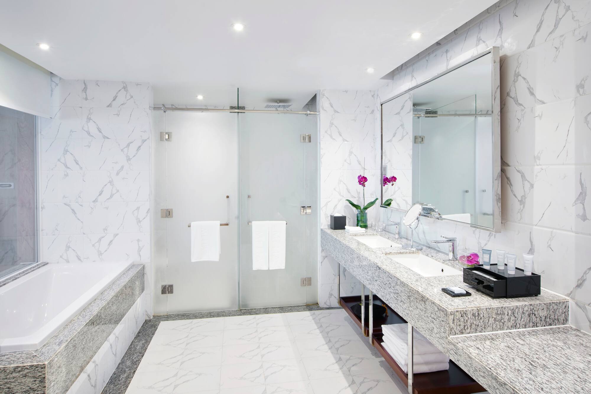 a bathroom with marble countertop sinks and a shower