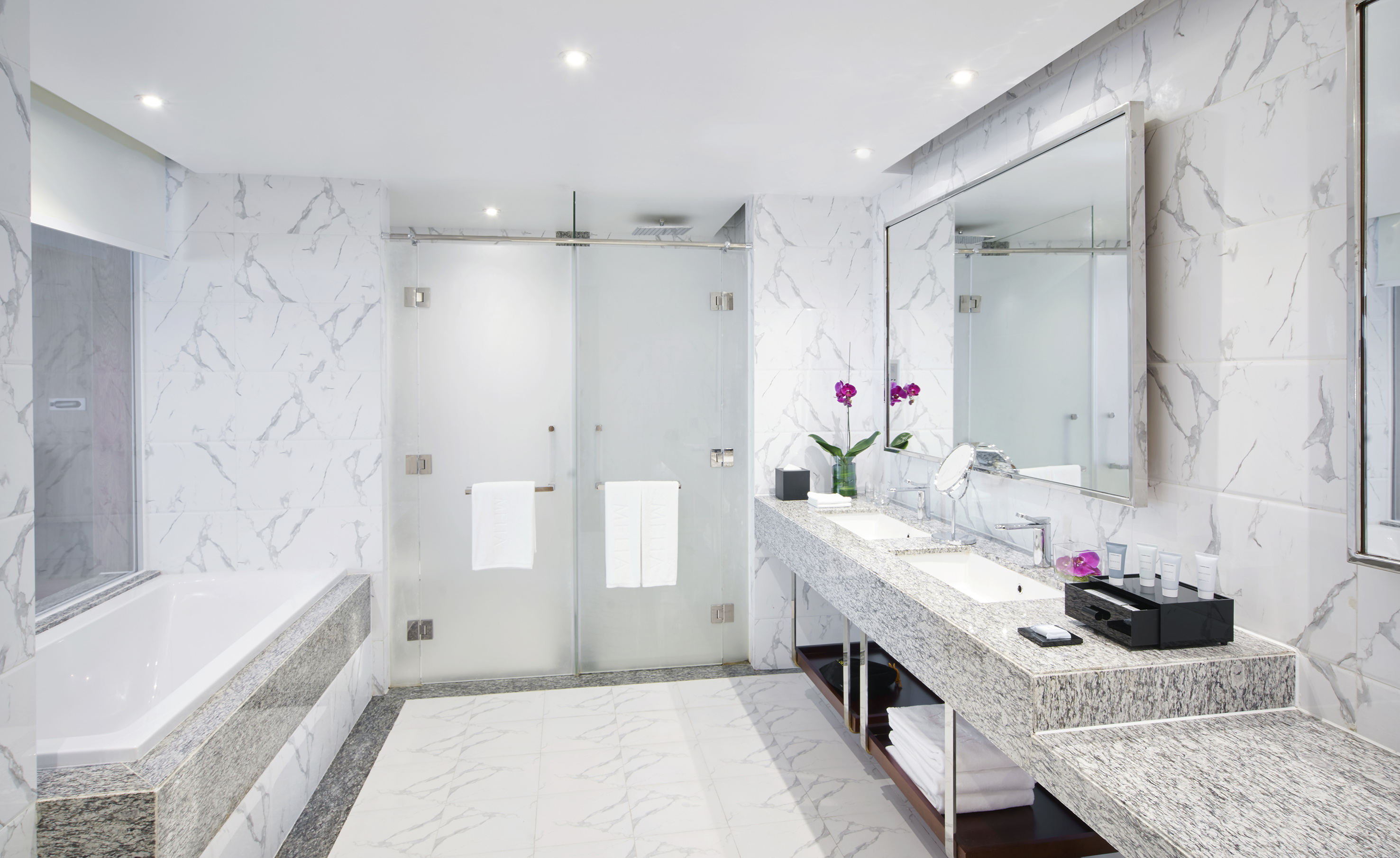 a bathroom with marble countertop sinks and a shower