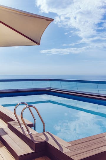 a pool with a deck and a railing overlooking the ocean