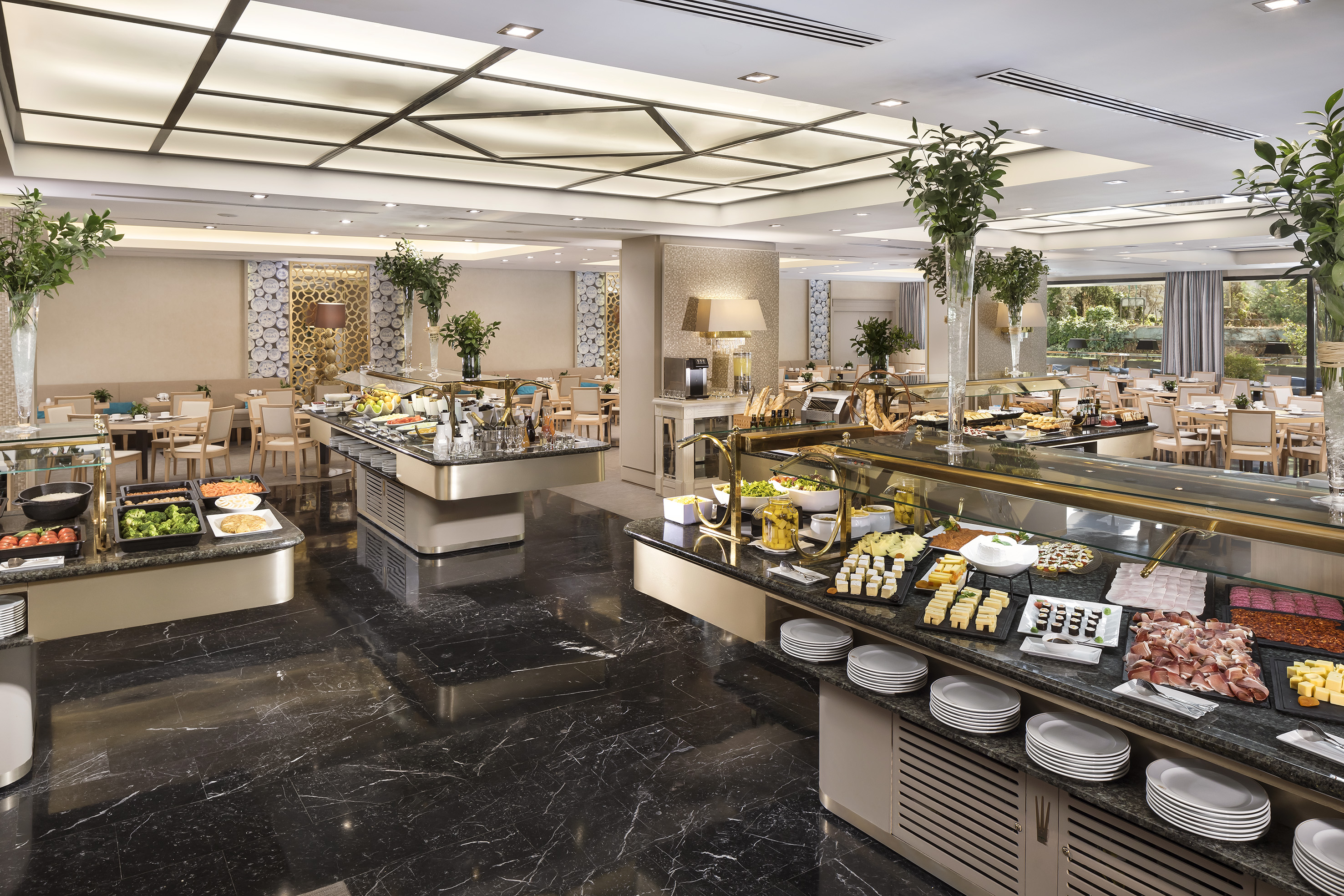 Elegant hotel buffet with food stations, black marble floor, and dining area.