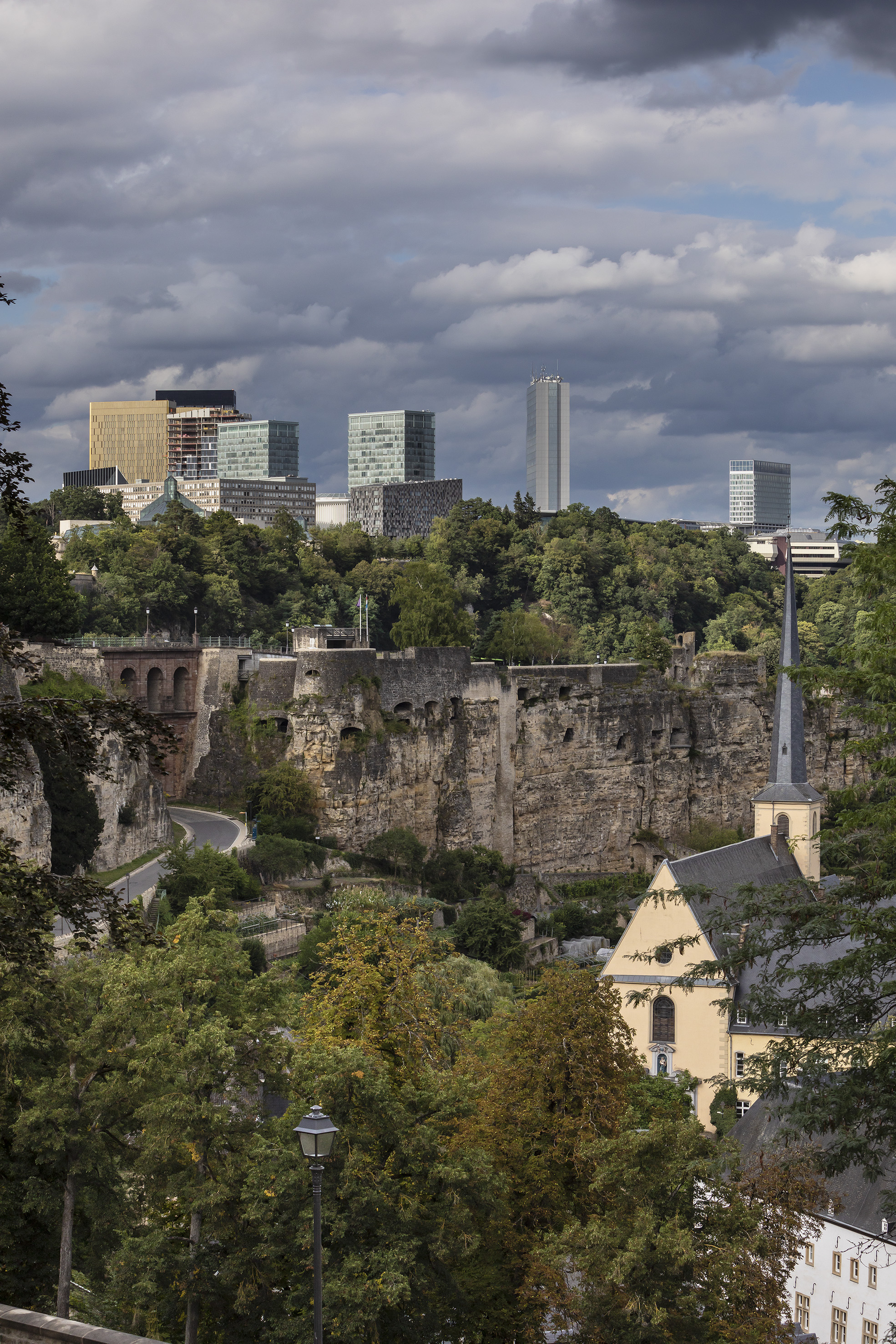 Luxembourg City: modern towers, historic fortifications, church, green valley.