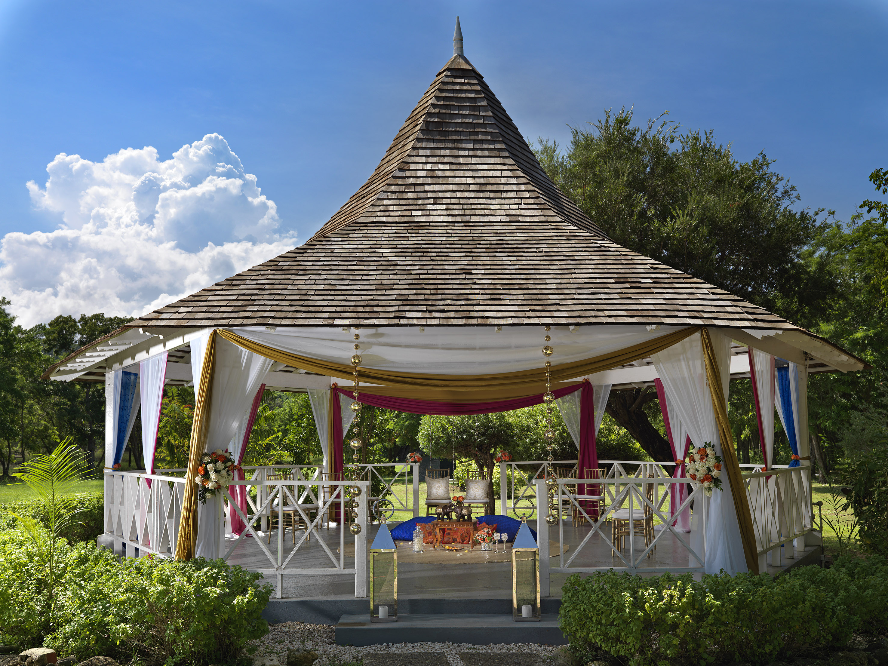 a gazebo with a table and chairs with Global Vipassana Pagoda in the background
