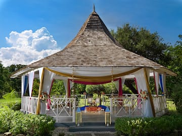 a gazebo with a table and chairs with Global Vipassana Pagoda in the background