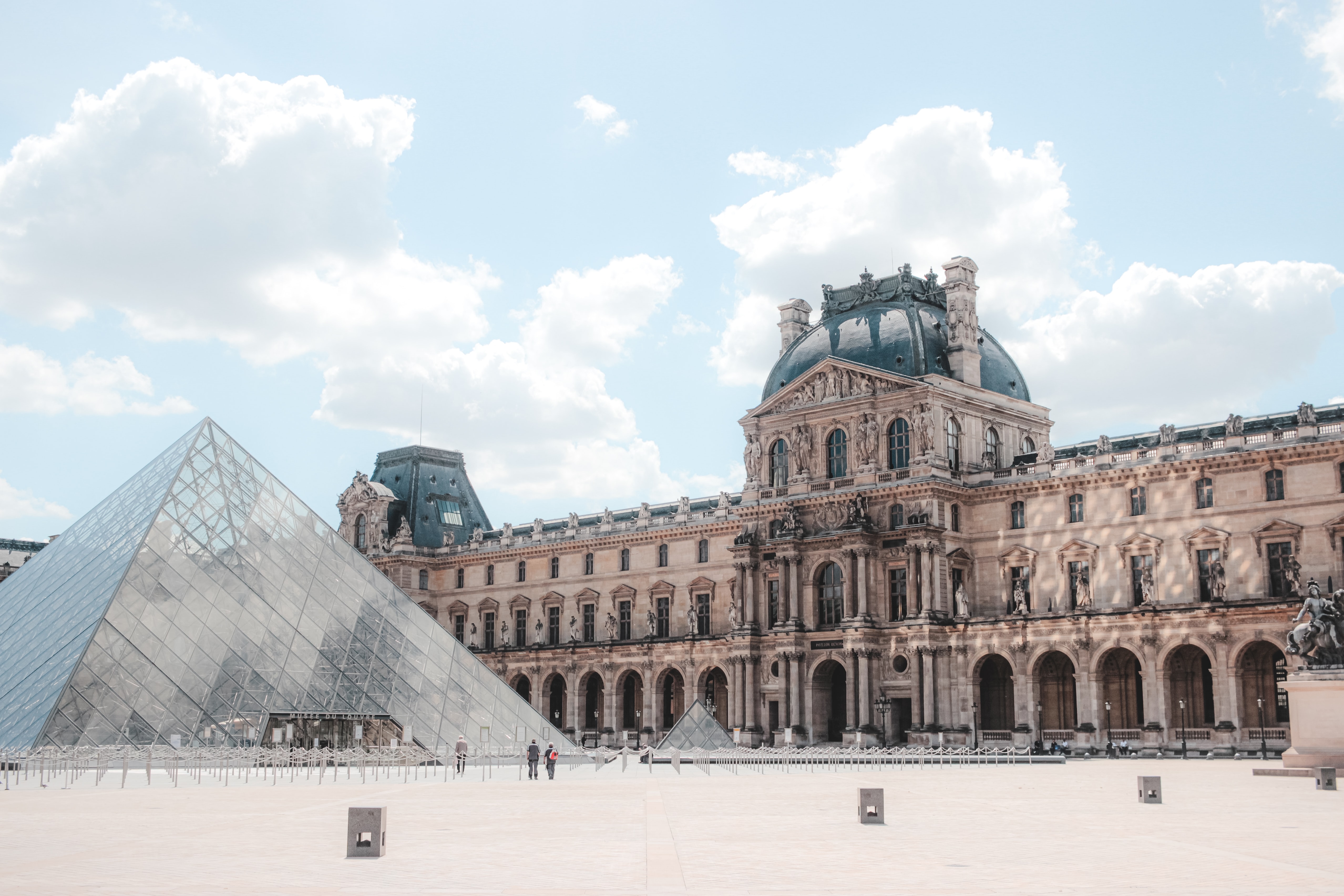 Louvre Museum glass pyramid and historic palace architecture in Paris.