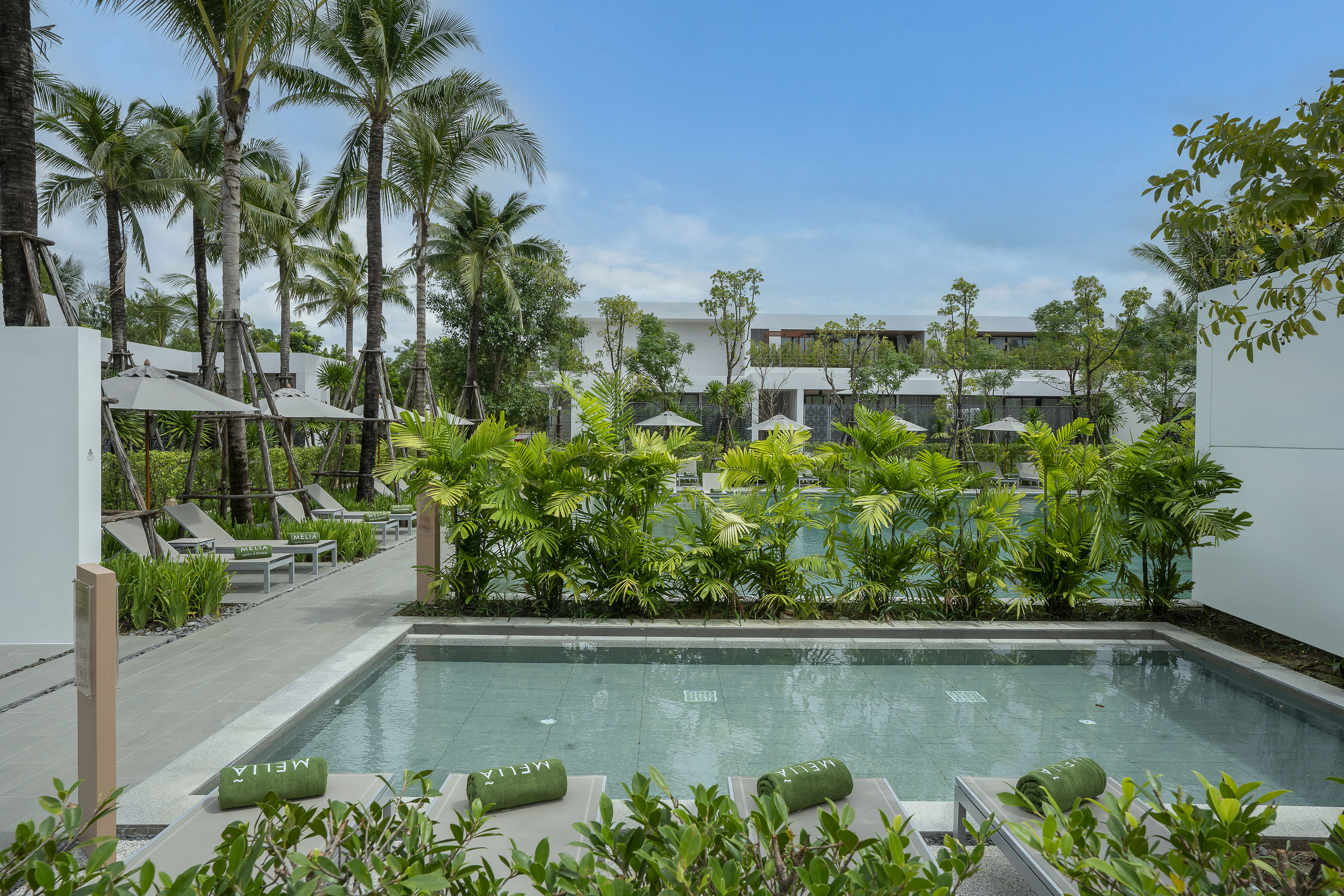 Melia resort pools, palm trees, sun loungers, tropical landscaping.