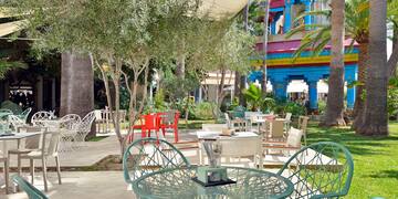 a table and chairs outside with trees and buildings in the background