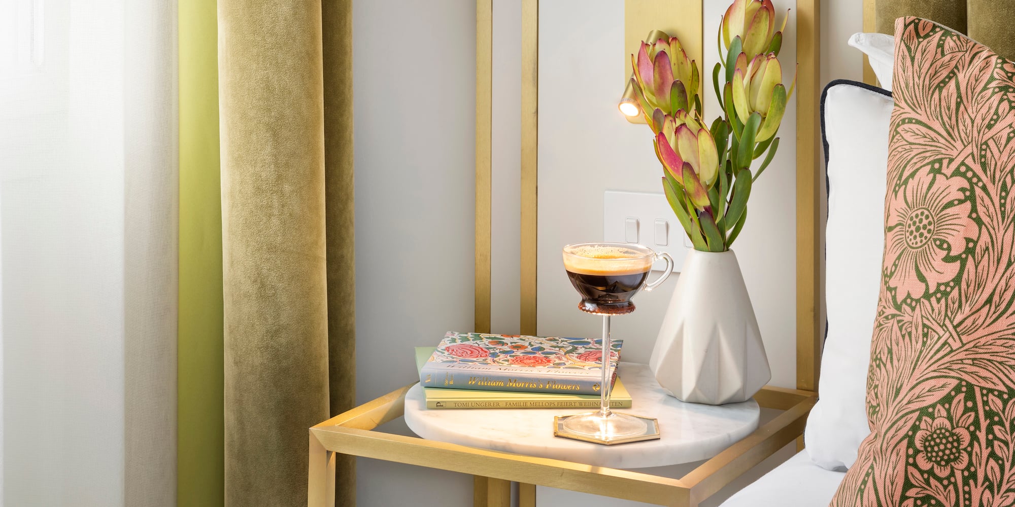 a coffee cup on a table next to a vase of flowers