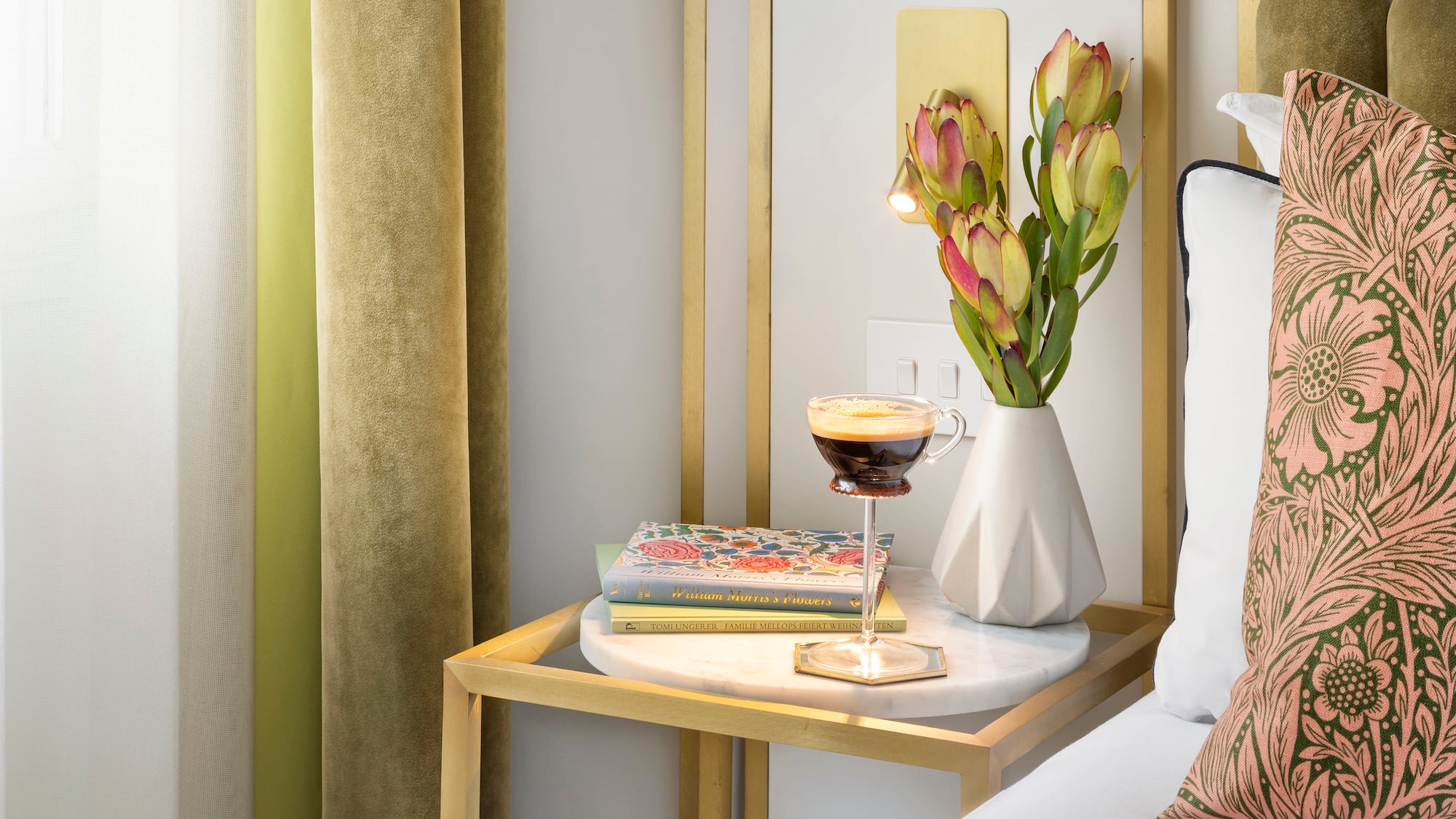 a coffee cup on a table next to a vase of flowers