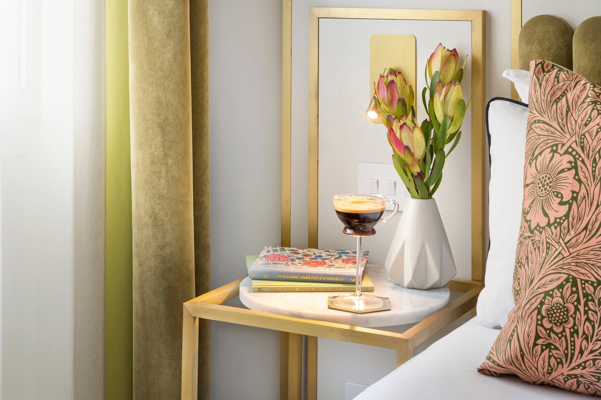 a coffee cup on a table next to a vase of flowers