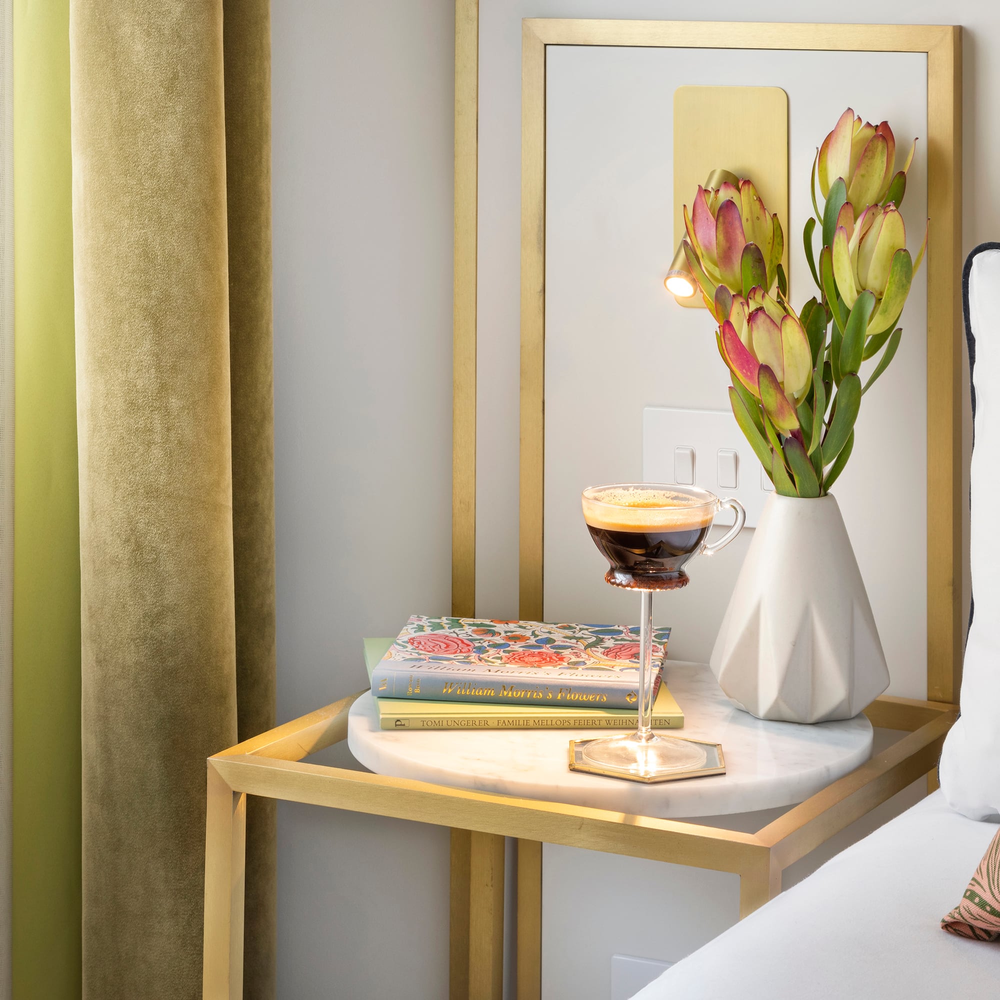 a coffee cup on a table next to a vase of flowers