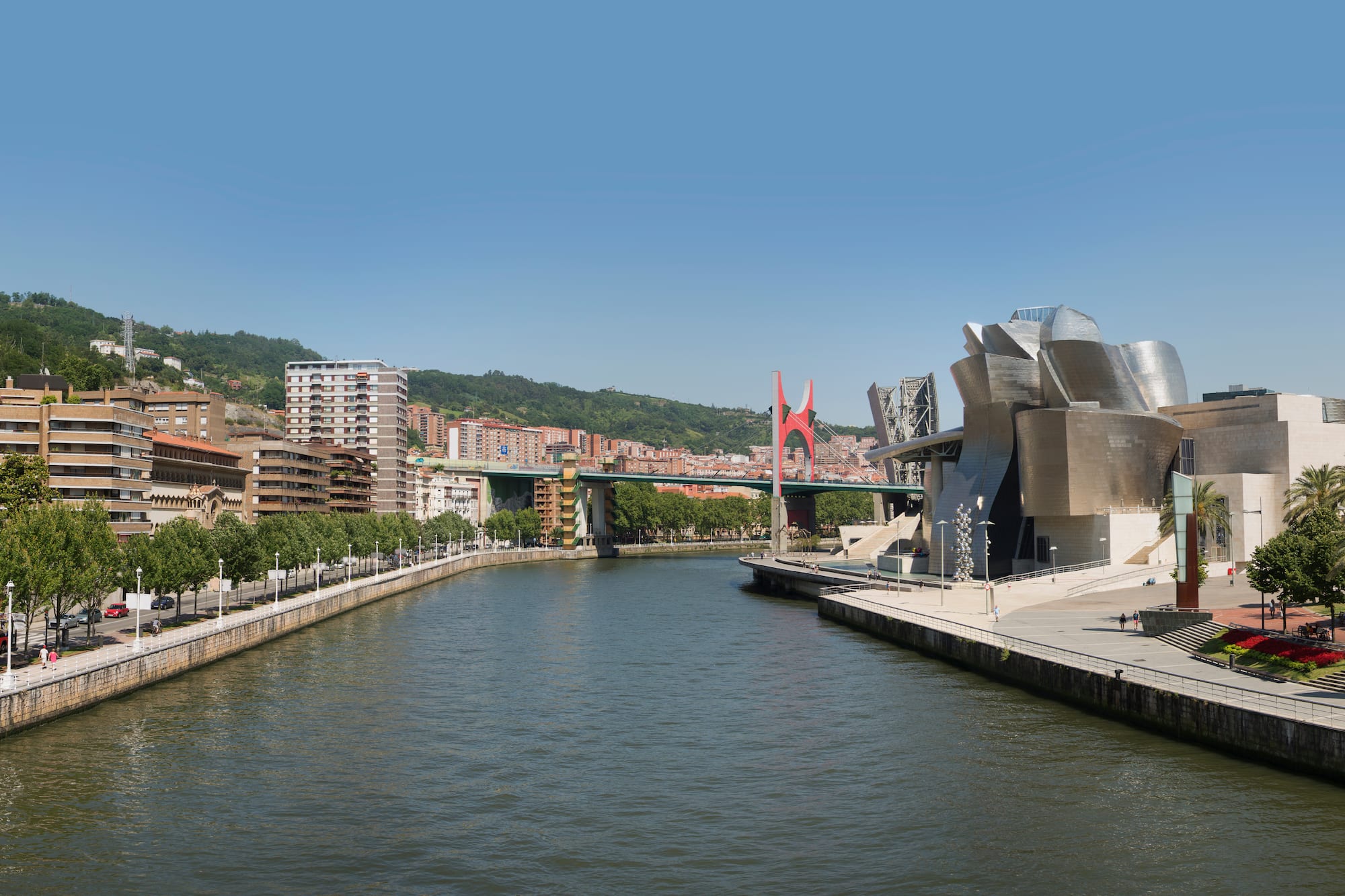 a river with a bridge and buildings in the background