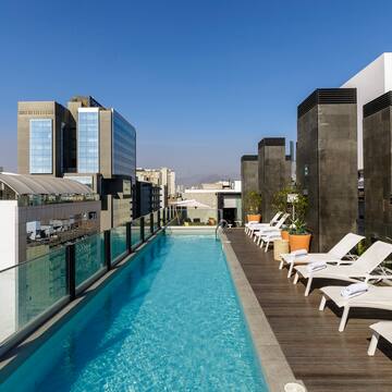 a pool with chairs and a deck on a rooftop