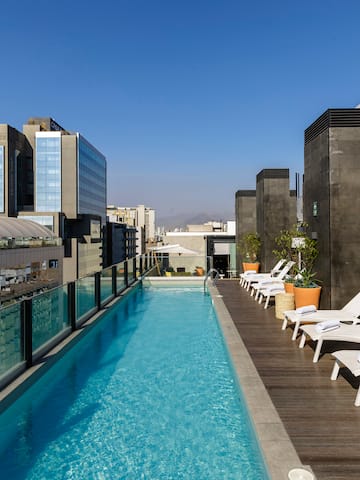 a pool with chairs and a deck on a rooftop