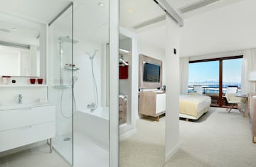 a bathroom with a glass shower and a bed