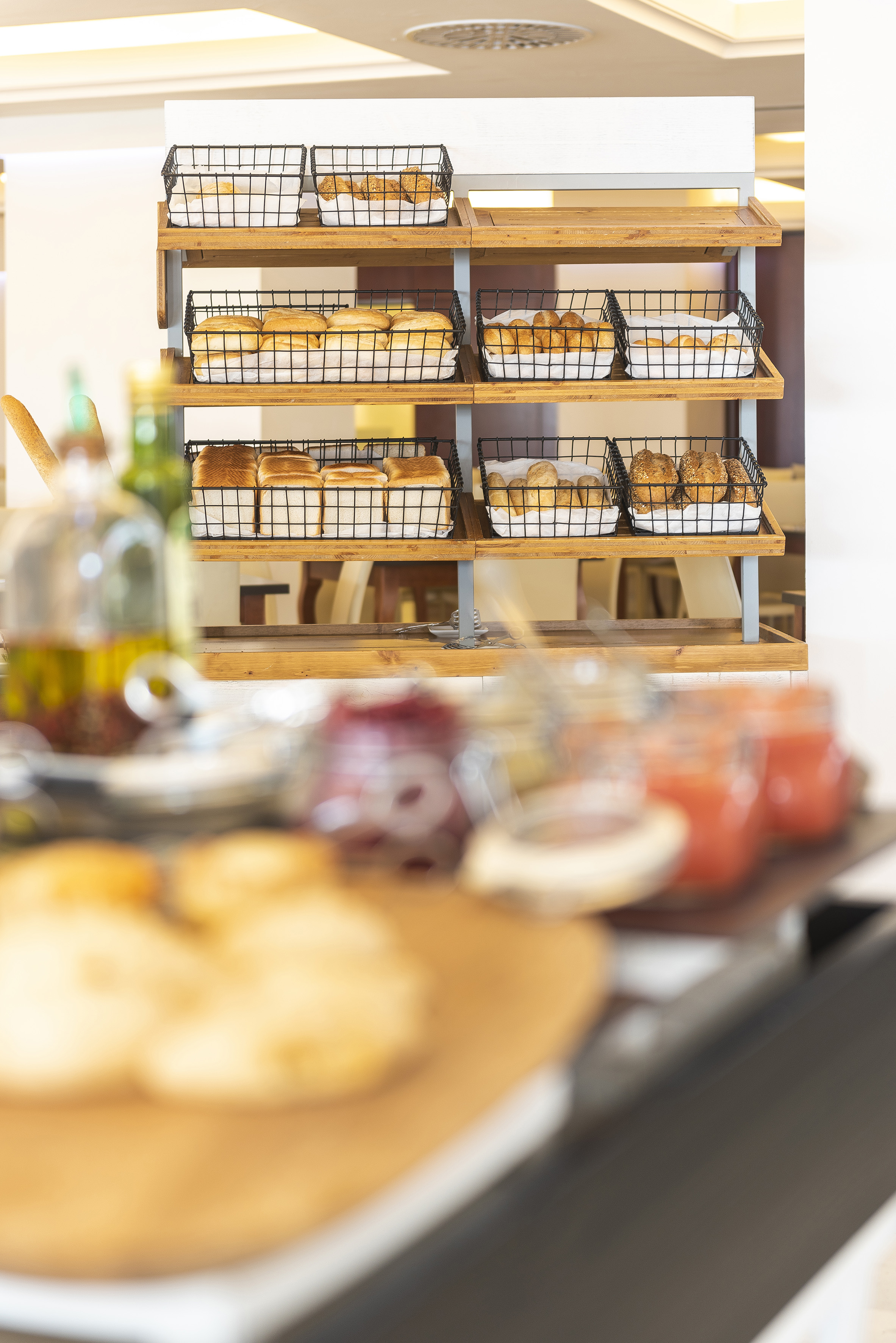 Breakfast buffet: assorted fresh bread, rolls, and pastries in wire baskets.
