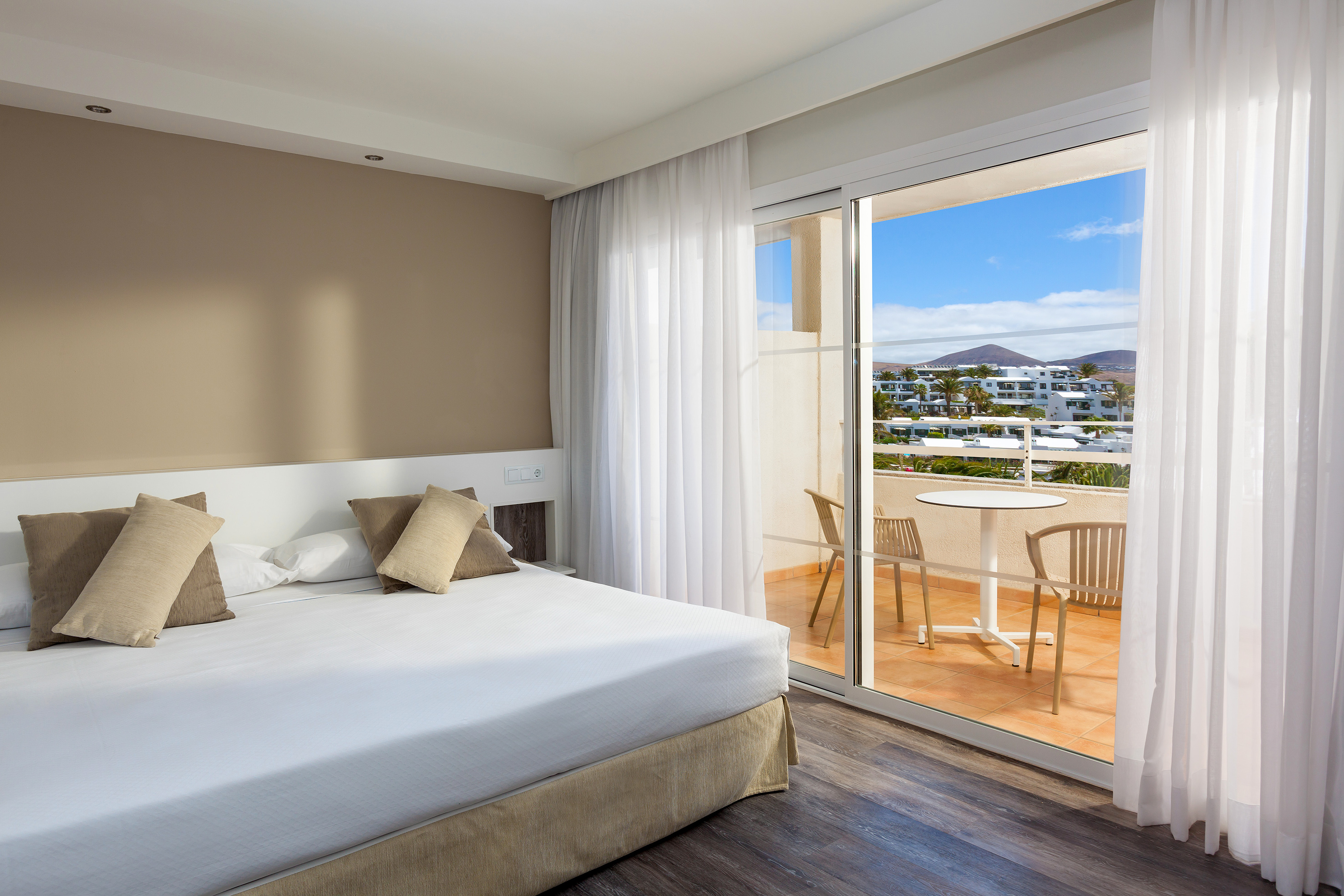 Modern hotel bedroom with balcony and scenic resort view.