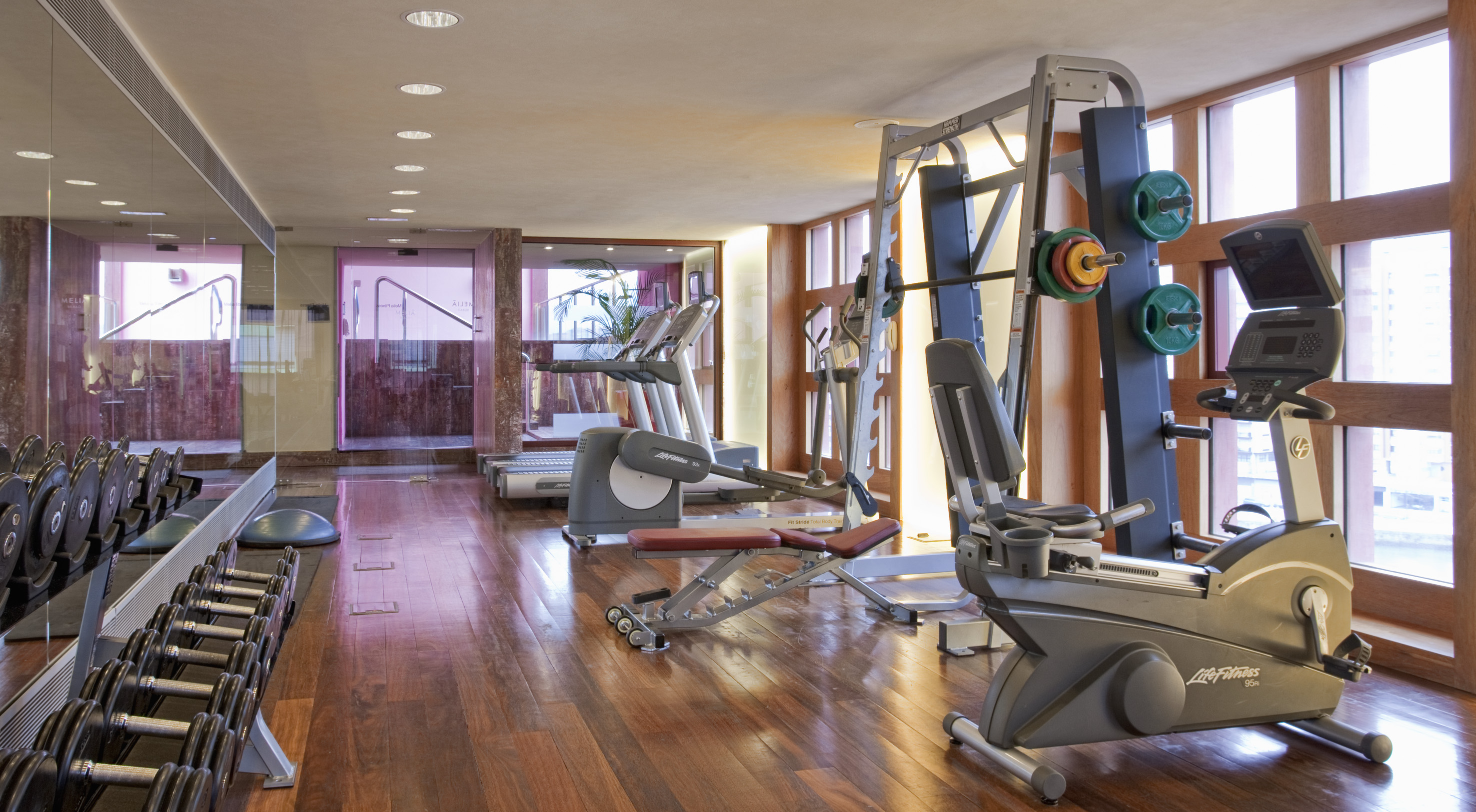 Well-equipped gym with dumbbells, treadmills, elliptical, and weight machine.