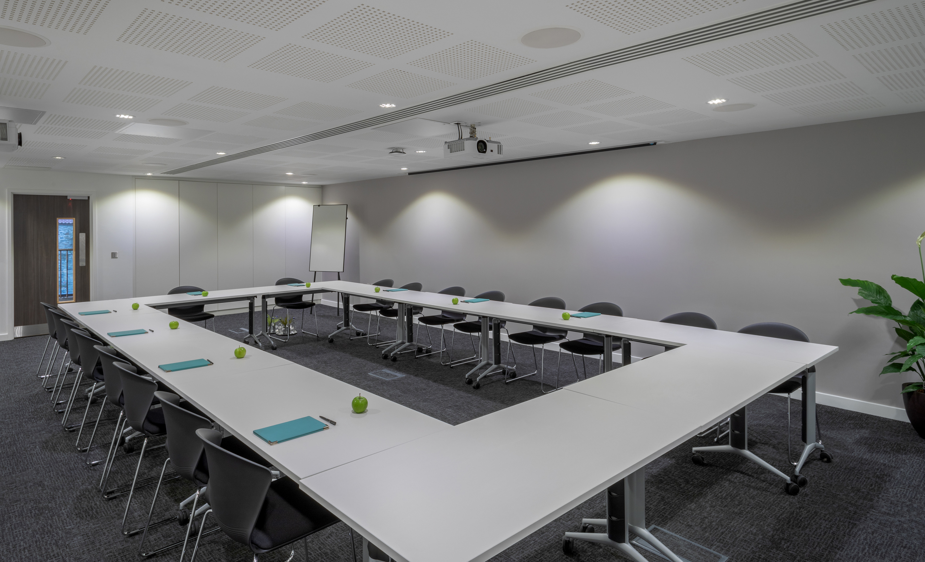 Professional conference room with U-shaped table, projector, and whiteboard.