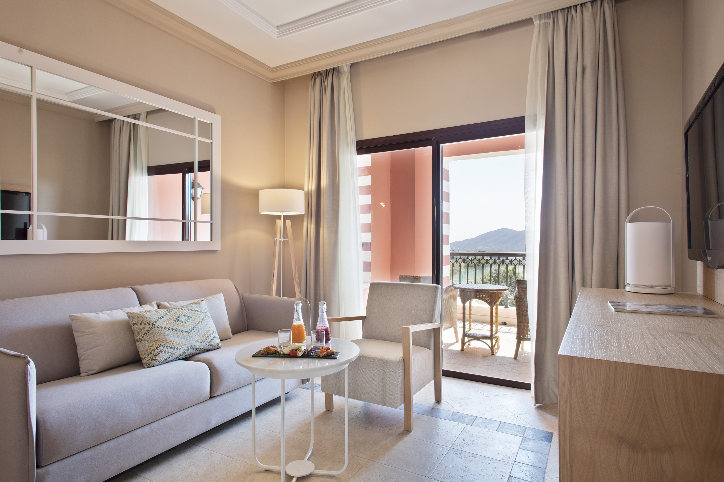 Hotel room living area with sofa, balcony mountain view, and breakfast.