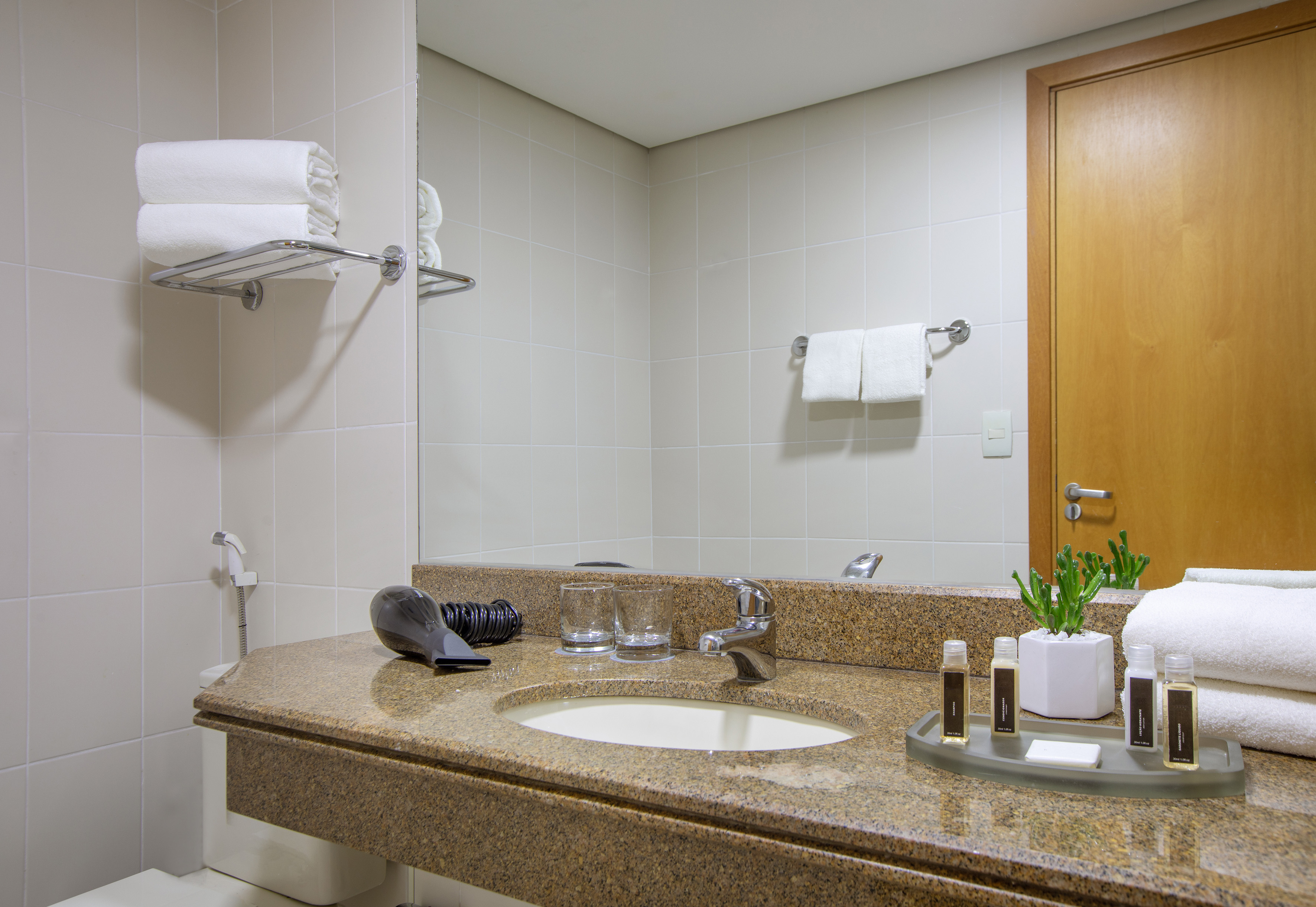 Modern hotel bathroom with granite counter, sink, clean towels, and toiletries.