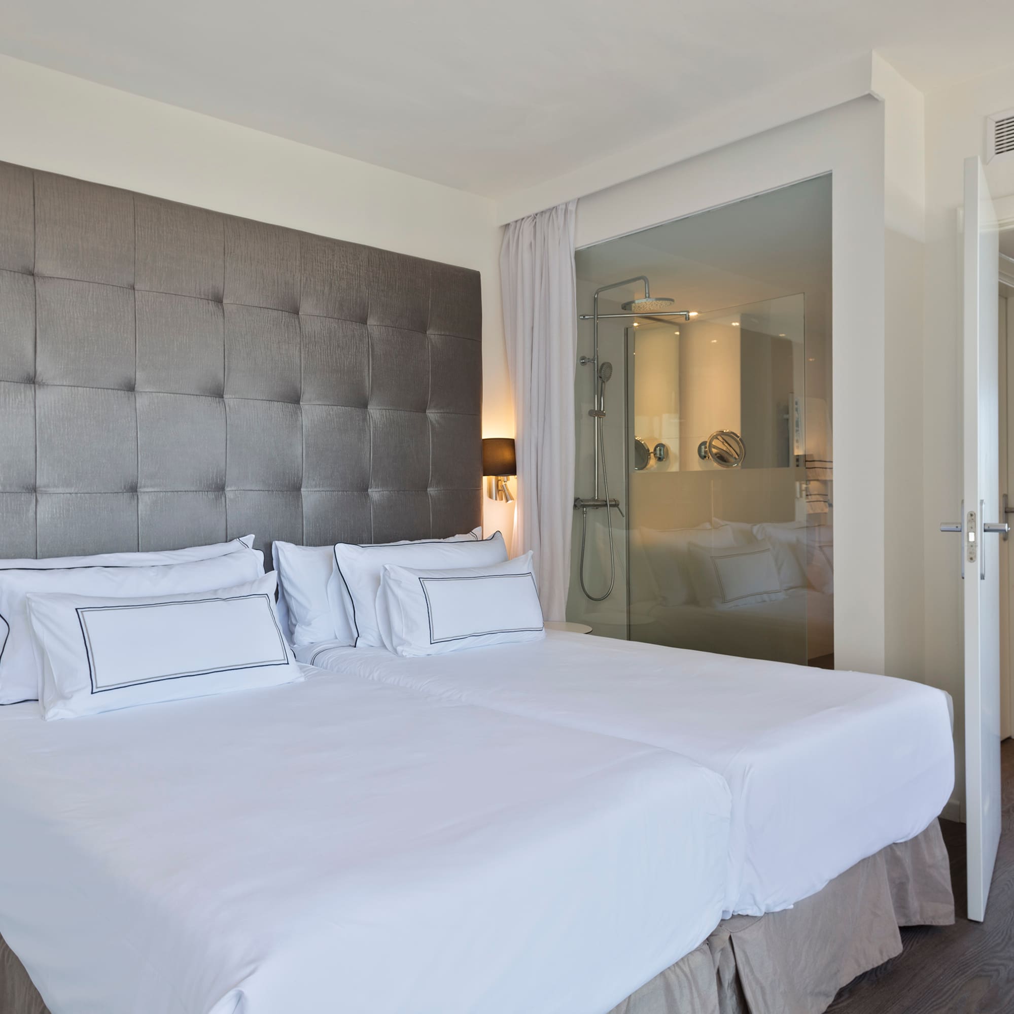 a bed with white sheets and a glass door