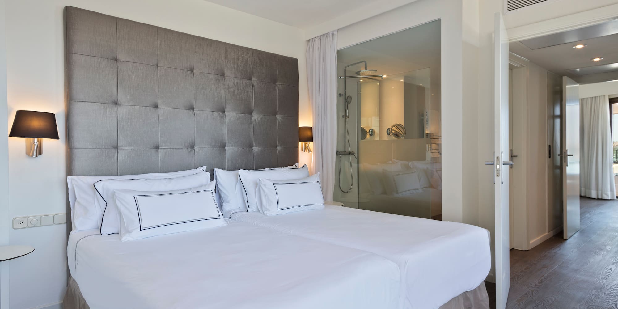 a bed with white sheets and a glass door