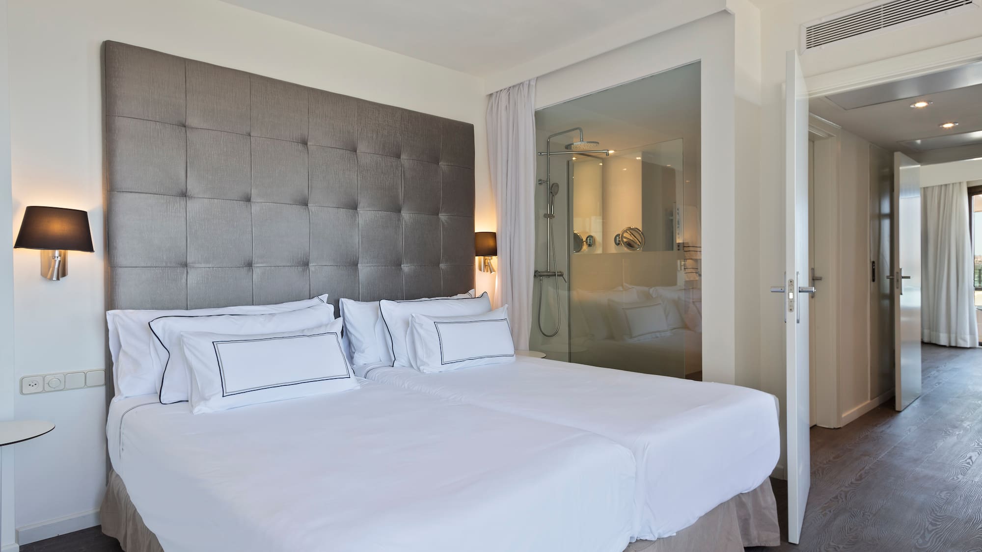a bed with white sheets and a glass door