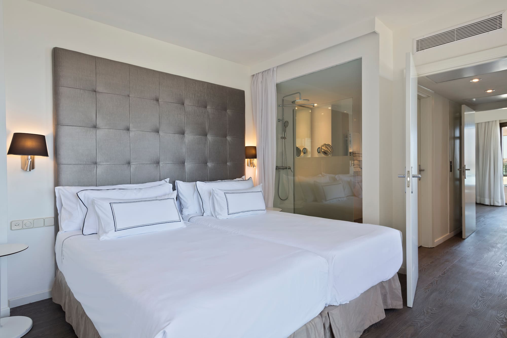 a bed with white sheets and a glass door