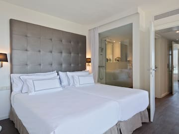 a bed with white sheets and a glass door