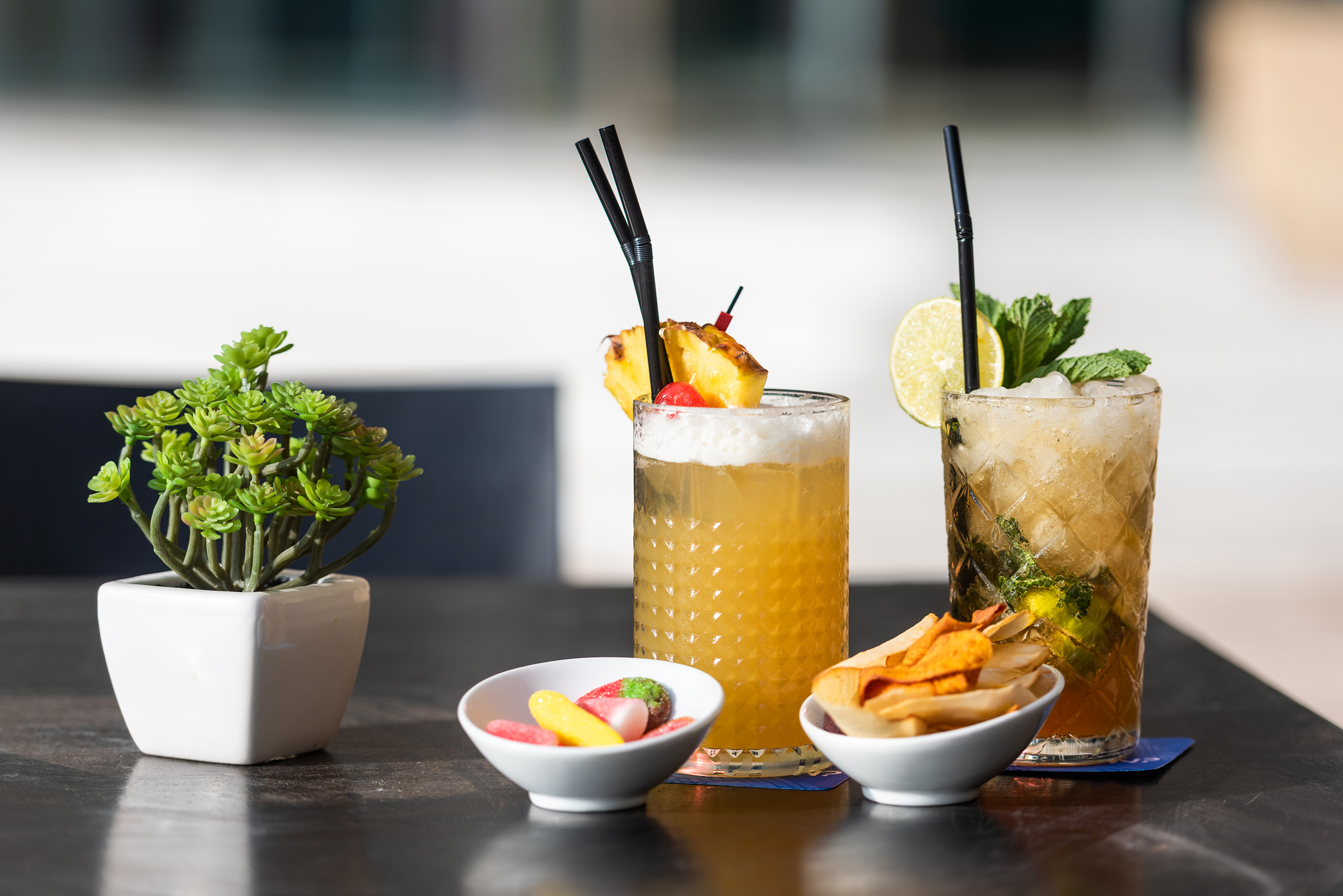 Refreshing cocktails with pineapple, lime, mint, and assorted snacks.